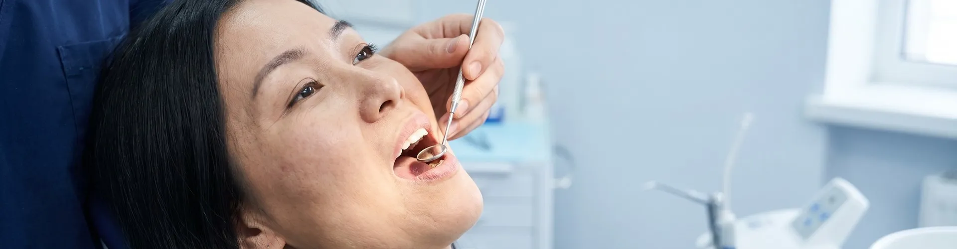 Dentist using a dental mirror to examine a patients teeth for cavity fillings.