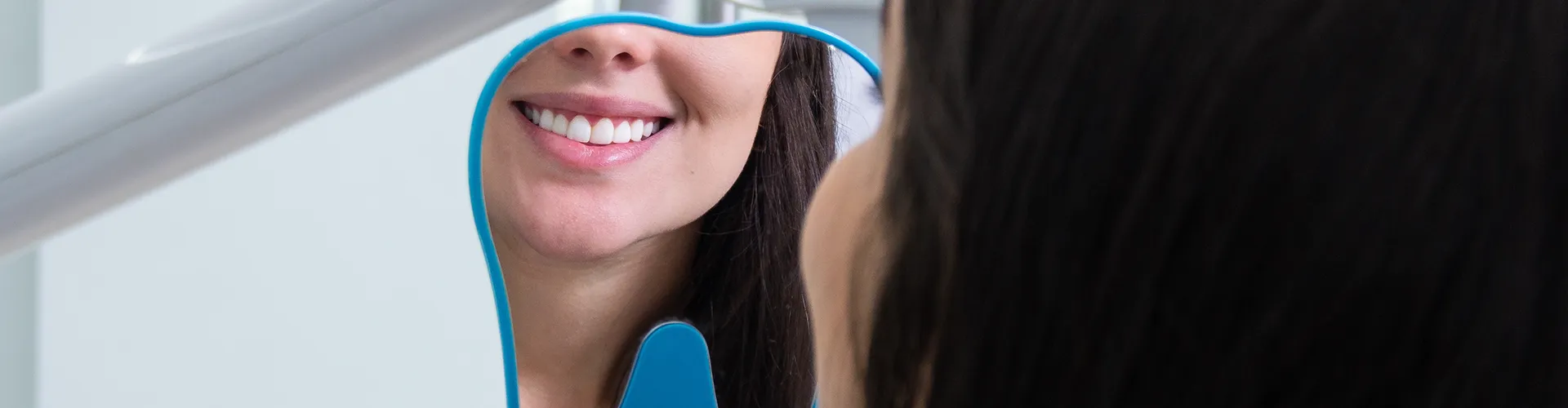 woman smiling into hand mirror