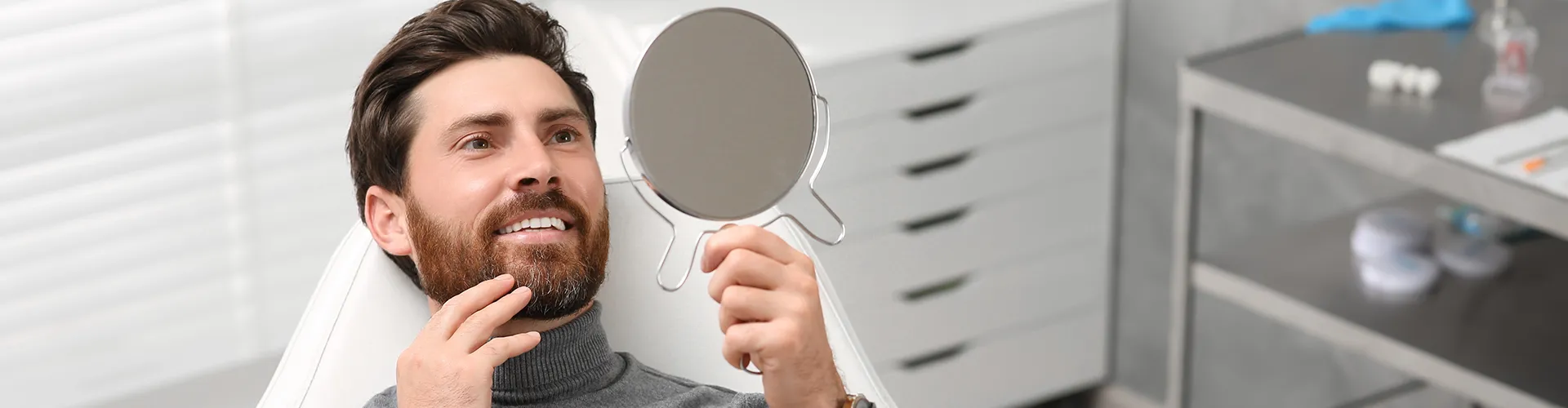 man smiling into hand mirror