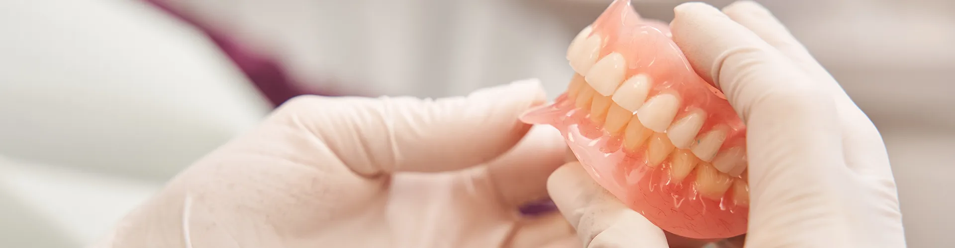 gloved hands holding a set of dentures