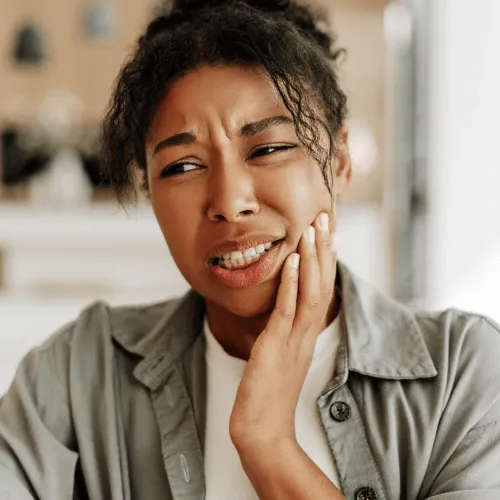 Woman holding her cheek in pain.