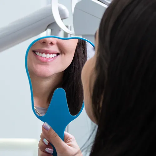woman smiling into hand mirror