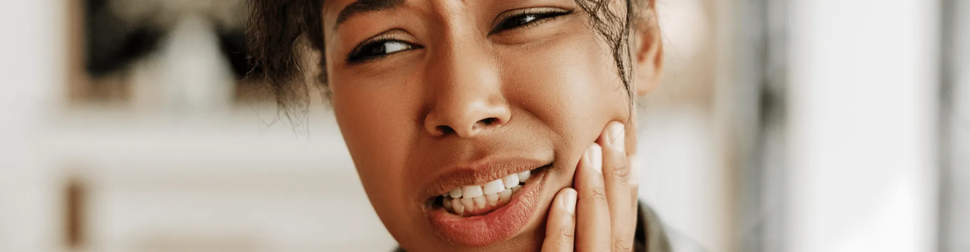 Woman holding her cheek in pain.
